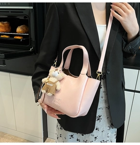 Pink bucket bag with embossed MUHETI letters and a cute plush bear charm accessory