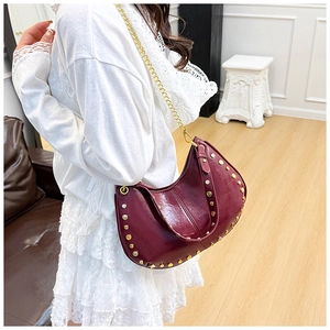 Detail of burgundy wax leather crescent bag with golden studs and metal chain strap