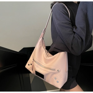 Detail of pink hobo tote bag featuring multiple zippers and silver rivets on textured leather