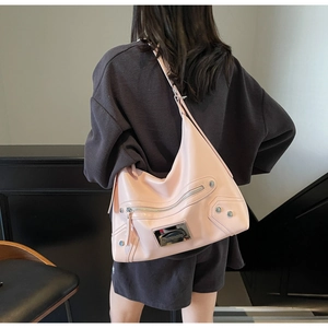 Gros plan détaillé d'un sac hobo en cuir rose avec des rivets argentés et des fermetures éclair