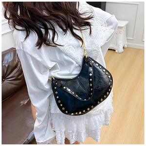 Close-up of black rivet shoulder bag with gold studs and textured vintage synthetic leather
