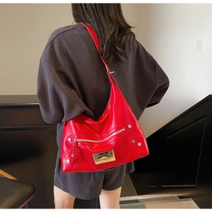 Close-up of a red glossy leather tote bag with silver zippers and motorcycle style rivets