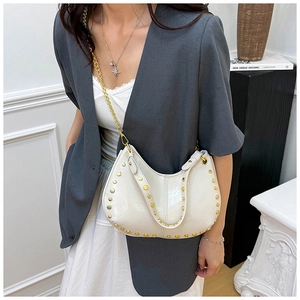 Detail view of white crescent bag with gold rivets and leather chain shoulder strap