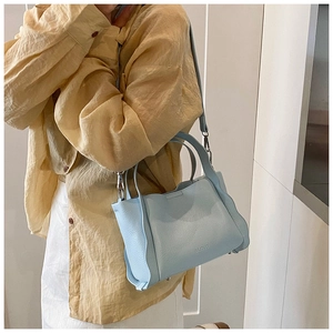 Detail of light blue bucket bag with lychee grain leather and metal feet studs