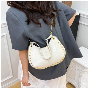 Detail view of white half-moon bag with gold studs and a stylish metal chain strap