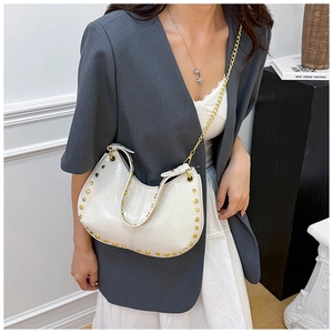 Detail of white moon hobo bag with gold rivets and chain strap on a model