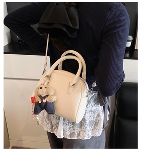 Detail shot of Korean style minimalist lychee pattern handbag with cute bear plush pendant.