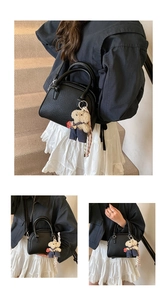 Details of the black litchi grain handbag featuring a cute teddy bear plush charm and strap.