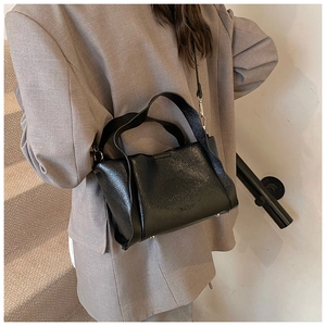 Detail of lychee pattern leather handbag with silver protective feet and MOPO brand logo