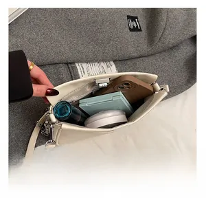 Dettaglio della capacità interna della borsa a tracolla in pelle crema con vari oggetti