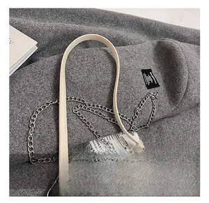 Dettaglio borsa in pelle beige con tracolla a catena argentata e fibbia quadrata in metallo