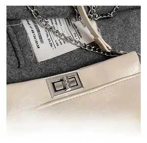 Dettaglio della chiusura a girello argento e catena metallica su borsa in pelle beige