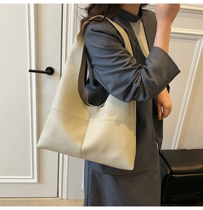 Detail of beige pebble leather hobo bag with stitching on a model in a minimalist setting
