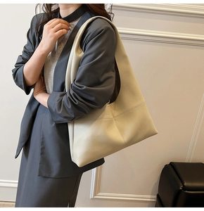 Close-up of minimalist cream tote bag showing premium lychee texture and stitched detail