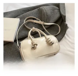 Détail du sac crème avec poignée à nœud et accent de sphère en métal argenté