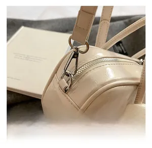 Détail du crochet métallique argenté et du zip sur un sac à main blanc crème brillant