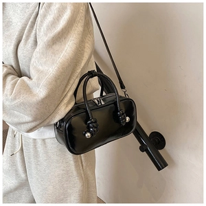 Détail du sac à main noir brillant avec perles argentées et poignée à nœud