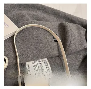 Détail d'un sac à main beige en cuir avec fermoir rotatif argenté et finitions de la bandoulière