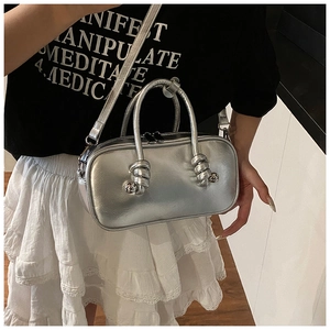 Détails d'un sac argenté brillant avec poignées à nœuds et fermeture éclair pratique