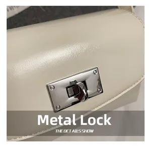 Détail macro du fermoir rotatif en métal argenté et coutures sur sac en cuir beige
