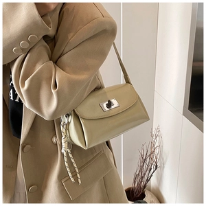 Détail d'un sac à bandoulière vert brillant avec fermoir argenté sur un blazer