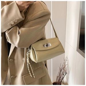 Détail d'un sac à main vert clair élégant avec fermoir métallique et sangle tressée