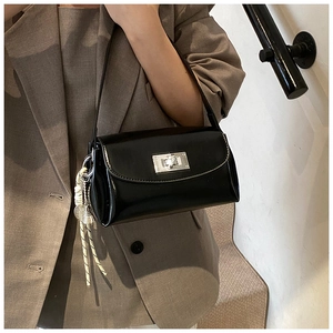Détail du sac à bandoulière noir brillant avec fermoir rotatif argenté et pendentif corde