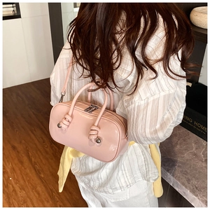 Détail d'un sac à main en cuir verni rose avec poignée nouée et décor de boules métalliques