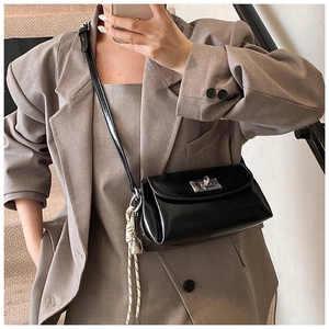Selfie miroir montrant un sac bandoulière noir brillant avec breloque coquillage