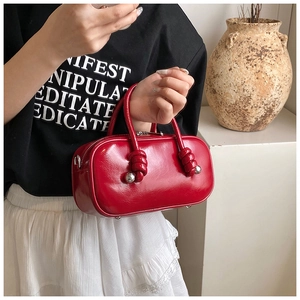 Détail du sac à main rouge en cuir brillant avec anse nouée et boules argentées pour femmes