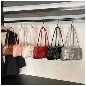 Detail view showing multiple colors of oil wax leather shoulder bags hanging on rack.
