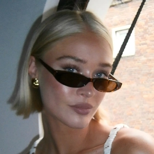 Close-up of retro narrow oval sunglasses in dark tortoiseshell with golden stud earrings