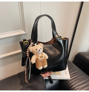Detail der schwarzen glänzenden Lederhandtasche mit Bärenanhänger auf einer Modezeitschrift