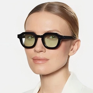 Modische Polygon-Sonnenbrille mit schwarzem Rahmen und gelb-grünen Gläsern bei einer Frau