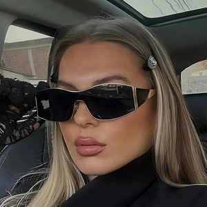 Fashion oversized shield sunglasses with black lenses and gold metal trim on female model