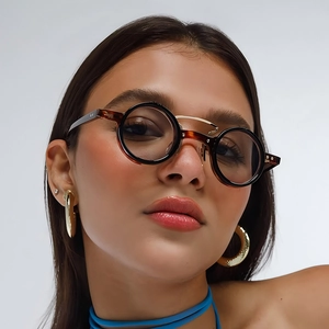Retro round tortoise shell sunglasses with gold bridge worn by a model on grey background