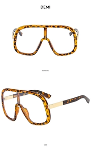 Detail view of large tortoise shell sunglasses with gold metal temples and demi frames