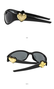 Detail view of oval sunglasses showing the gold heart and floral accents on black side temples