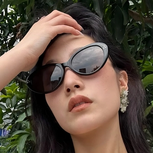 Modische ovale Katzenaugen-Sonnenbrille mit schwarzem Rahmen und Nieten im Freien