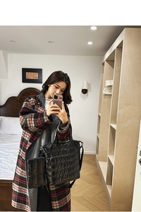 Quilted puffer tote bag in black styled with a classic plaid coat for winter fashion