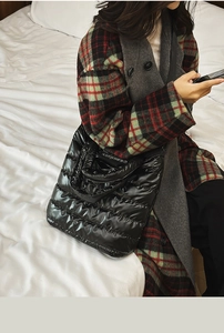 Lifestyle view of a large black glossy quilted tote bag shown in a cozy home setting