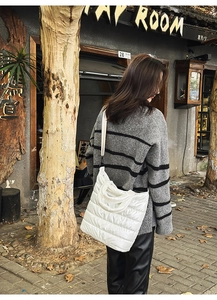 Outdoor shot showing white quilted puffer tote bag with large square pattern on shoulder