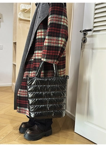 Detail of black quilted puffer tote bag showing padded texture and carry handle