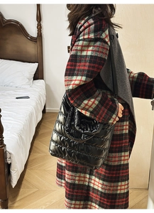 Close-up of a large black quilted tote bag with padded texture and adjustable strap