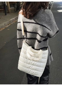 Street style view of a white quilted down tote bag with detachable wide strap for women