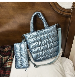 Close-up of quilted tote bag and matching pouch in metallic blue on cozy bed setting