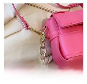Gros plan détaillé d'un sac bandoulière tissé rose avec chaîne dorée et boucle métallique