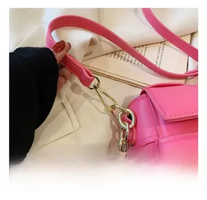 Détail du sac bandoulière rose fuchsia montrant le crochet doré et la bandoulière en chaîne