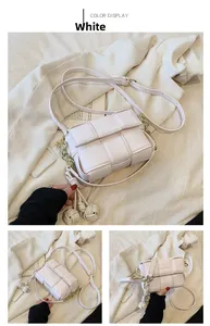 Détails macro d'un sac bandoulière blanc tissé avec chaîne dorée et charms tressés