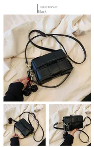 Détail du sac à bandoulière tressé noir avec breloques nœuds et chaîne en métal